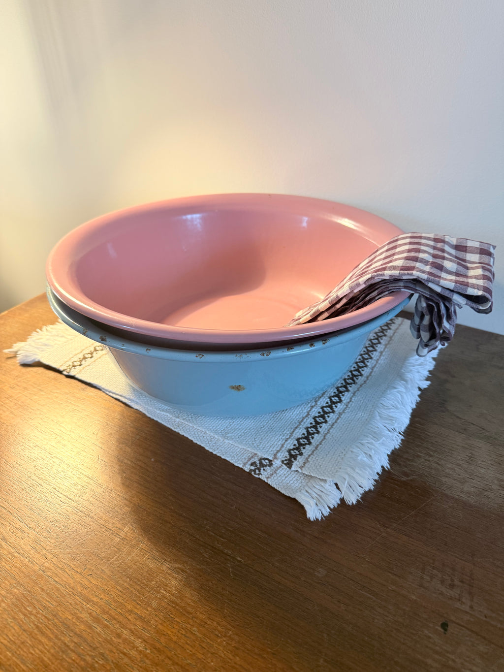 Two vintage enamel basins in soft blush pink and powder blue